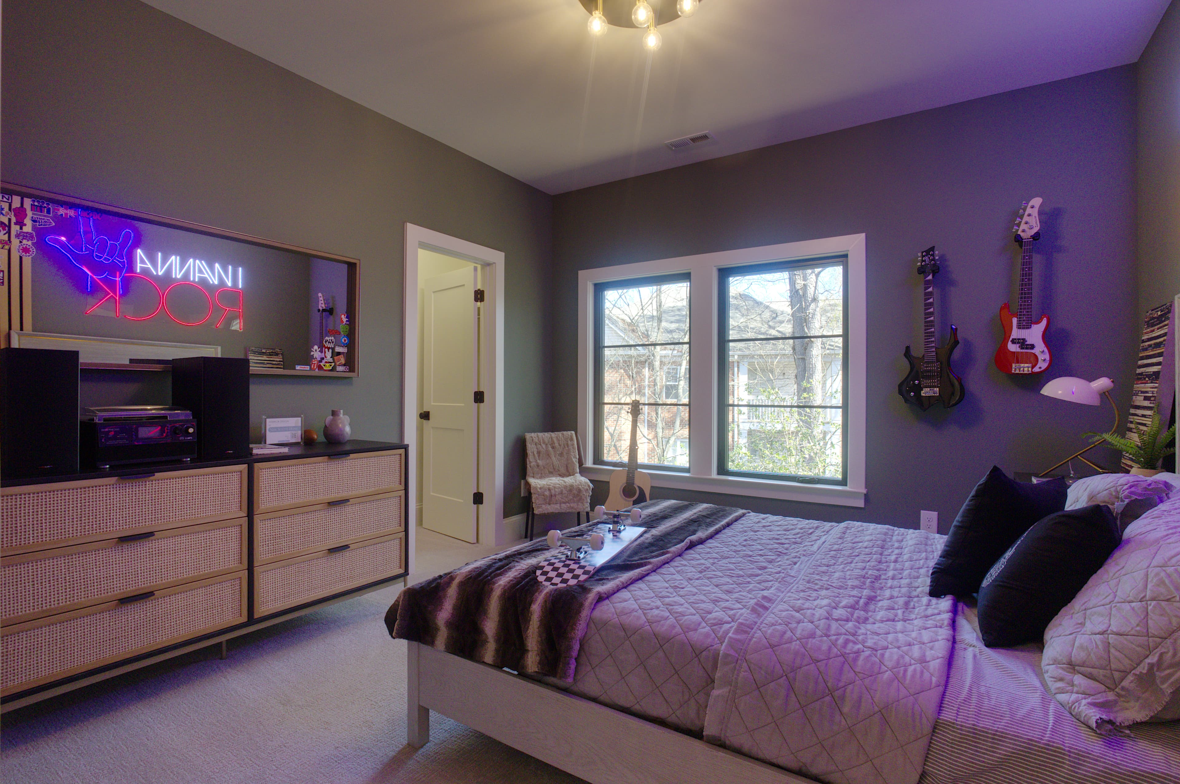 Rock-themed bedroom with purple lighting, wall-mounted guitars, and a neon "I WANNA ROCK" sign.